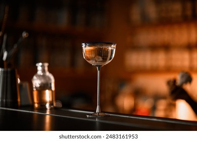 Cocktail glass with a tall metal stem standing on a bar counter - Powered by Shutterstock