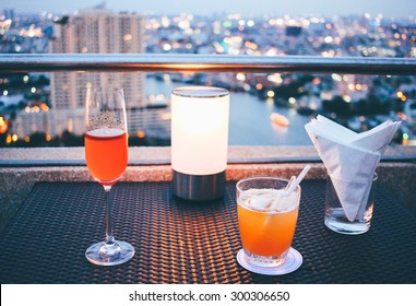 Cocktail Glasses With Candle Light In Rooftop Bar Against City View