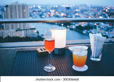 Cocktail Glasses With Candle Light In Rooftop Bar Against City View