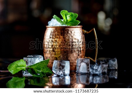 Cocktail with ice, in a copper mug on a black background.