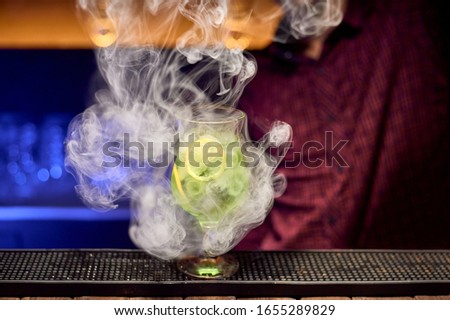 A cocktail of lime and mint on the nightclub bar is filled with white smoke.