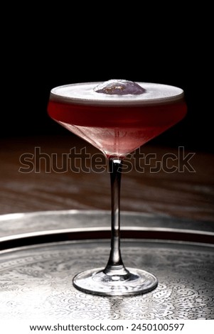Cocktail in a martini glass on a dark background.