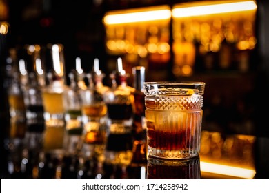 A Cocktail In An Old Fashioned Glass On A Bar Counter With A Reflection, Bottles With Bitters, Bokeh Lights, Horizontal Photo