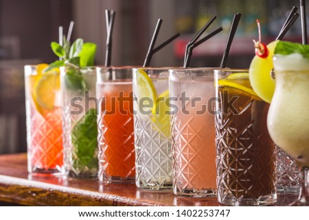 Cocktail on the bar. Whiskey-cola cocktail, pina colada, mojito-cocktail, orange cocktail, strawberry cocktail in glass glasses with straws. Bar accessories: shaker, spoon, spices on a wooden stand