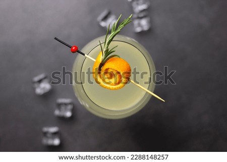 Cocktail on black table with ice cubes in background, orange garnish, flat lay, cocktail concept