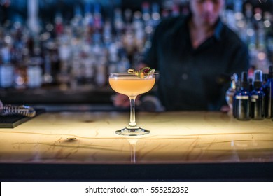 Cocktail On A Lit Up Bar With Bartender In Background 