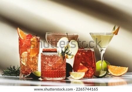 Cocktail party. Bright fruity and citrus alcoholic drinks with gin, vodka, vermouth and juice. Beige background, hard light, shadow pattern