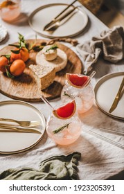 Cocktail Party Table Setting. Grapefruit Rosemary Margaritas In Glass, Cheese Fruit Board, Dinnerware, Cutlery On Linen Tablecloth. Romantic Table Setting For Celebration, Stay At Home During Lockdown