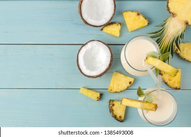 Cocktail Pina Colada. Pina Colada refreshing summer alcoholic cocktail with coconut milk and pineapple juice nearby. summer drink. cocktail preparation. on blue wooden background. top view
