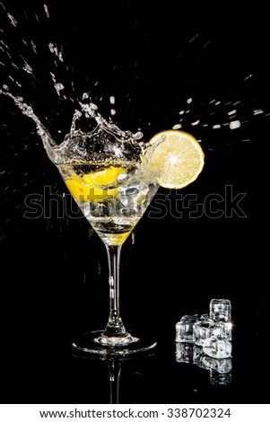 cocktail with splash and  lime isolated on black