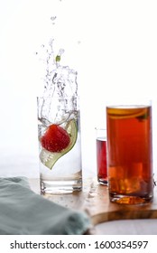 Cocktail Splash!  Spritzer Cocktail With Cucumber And Strawberry Splash.  Ice Tea And Pink Cocktail In Background White Background