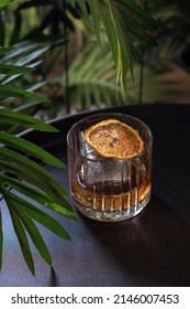 Cocktail In A Wide Glass With Whiskey And A Large Ice Cube And Citrus In A Bar