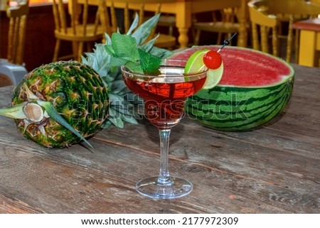 Cocktail Woowoo cherry, lime, mint, cranberry juice and vodka with watermelon and pineapple on the old wooden table.