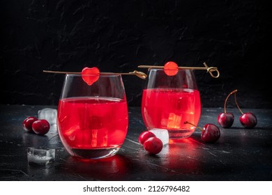 Cocktails with cherries. Alcohol drinks on a black background, with ice. Fancy beverage