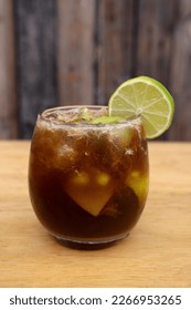 Cocktails. Closeup view of an alcoholic drink with Jägerinha, coke, ice and lime, with a wooden background. 