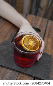 Cocktails. Closeup View Of A Female Hand Holding A Negroni Alcoholic Drink With A Dried Orange Slice And Ice. 