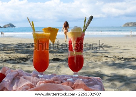 Cocktails with exotic fruits and ice cream in the shade of a beautiful beach in Costa Rica. Blurred background with pacificocean and young women 