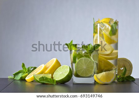 Cocktails with lime , lemon , ice and peppermint leaves on a black table .Copy space.