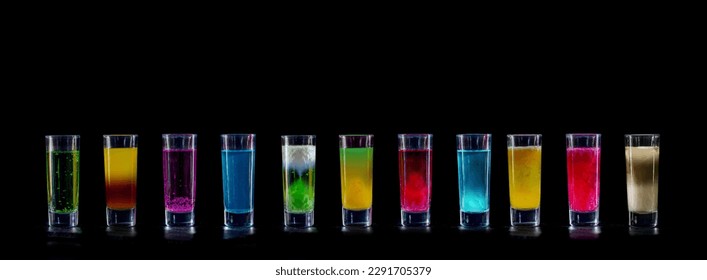Cocktails Party Shots and Shooters on bar counter in a restaurant, pub. Miniature mixed drinks. Alcoholic cooler beverage on black isolated background.