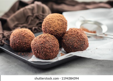 Cocoa balls, chocolate balls cakes in a black tray, sprinkled with cocoa powder.