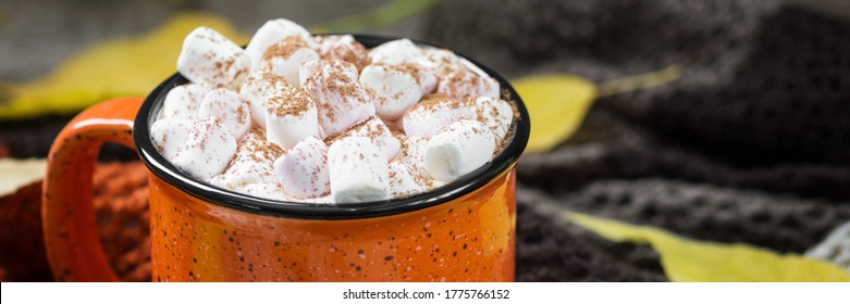 Cocoa with marshmallows in an orange mug on a wooden table. Autumn banner with space for text - Powered by Shutterstock