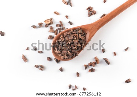 Cocoa Nibs into a spoon isolated on white background