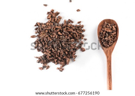Cocoa Nibs into a spoon isolated on white background