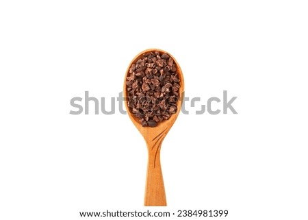 Cocoa nibs in spoon, close-up. Cacao nibs often added to cereals, cottage cheese, desserts, sorbets, smoothies, sweets, raw food and vegan dishes.