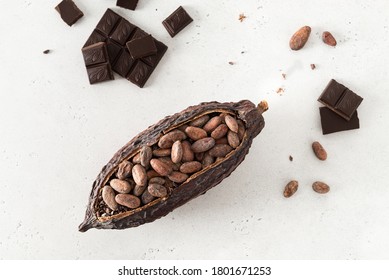 Cocoa pod with cocoa beans and pieces of chocolate on a white background. Organic food. Natural chocolate. Top view, flat lay. chocolatier, confectionery