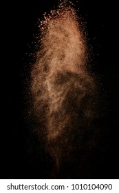 Cocoa powder explosion in motion. Chocolate dust on a black background. Action food photography.