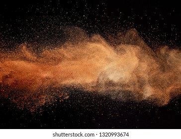 Cocoa powder explosion on black background.