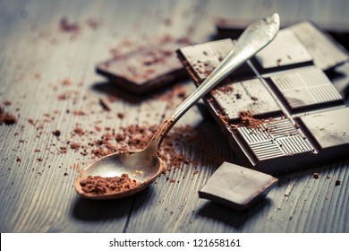 Cocoa Powder On Spoon And Dark Chocolate Background