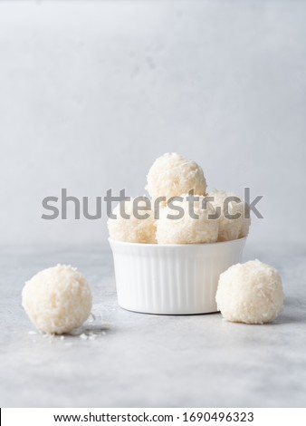 Coconut balls, raw and healthy sugar free rafaello candies. Vegetarian energy sweets recipe step by step. Round tasty dessert in ceramic bowl. Copy space, close up view. Healthy organic food for kids.