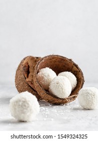 Coconut Bliss Balls In Coconut Shells On White Gray Background