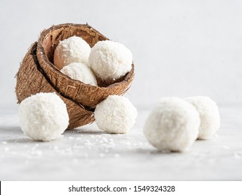 Coconut Bliss Balls In Coconut Shells On White Gray Background