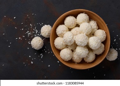 Coconut candies bowl on dark table background flat lay top view