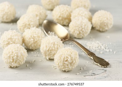 Coconut candies and spoon on wooden shabby background. Shallow DOF, focus on foreground.