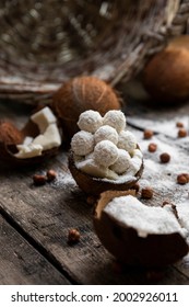 Coconut candy, balls, coconuts and hazelnuts on a rustic wooden surface