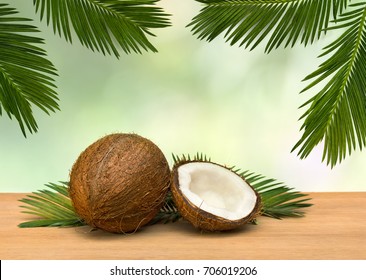 Coconut (Cocos nucifera) with half and palm leaves on wooden table on a background tropical leaves palm tree.