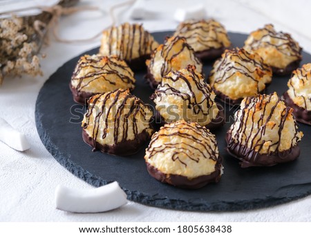 Coconut cookies in chocolate on a black plate.