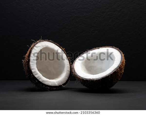 Coconut is\
divided in half on a black\
background