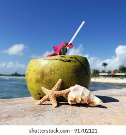 Coconut with drinking straw on a beach at the caribbean sea