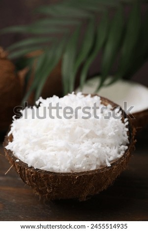Coconut flakes in nut shell on wooden table