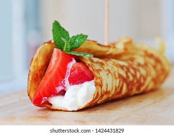 Coconut flour keto wraps with cottage cheese and strawberries. Low-carb gluten free crepe on cutting board, closeup.