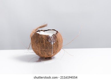 Coconut Full Of Milk Spilling Onto A White Table