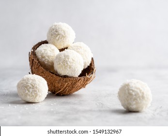 Coconut healthy sugarfree bliss balls in coconut shells on gray white background