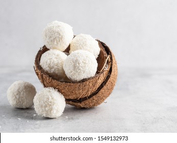 Coconut healthy sugarfree bliss balls in coconut shells on gray white background