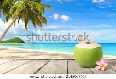 Coconut  juice on wooden table with beach and blue sky background.