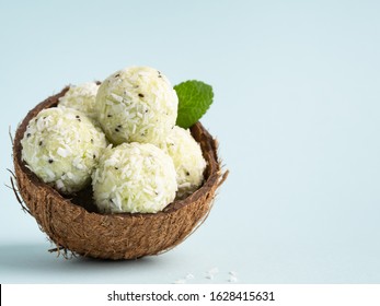 Coconut And Kiwi Energy Balls (bliss Balls) In Coconut Shell On Blue Background. Vegetarian Healthy Snack, Sugar Free Dietary Food. Place For Text, Copy Space.