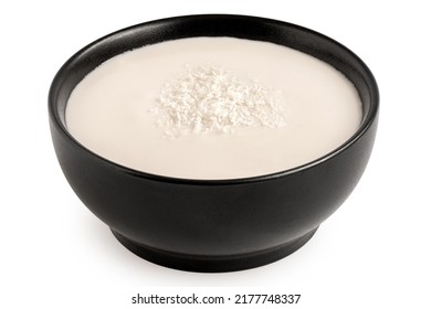 Coconut Milk In Black Ceramic Bowl Topped With Desiccated Coconut Isolated On White.